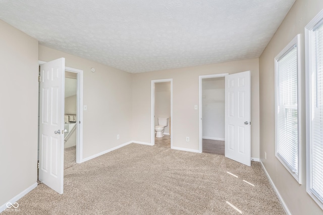 3515 Bearwood Ct, Indianapolis, IN 46235 - unfurnished bedroom featuring a walk in closet, light colored carpet, a textured ceiling, ensuite bath, and a closet
