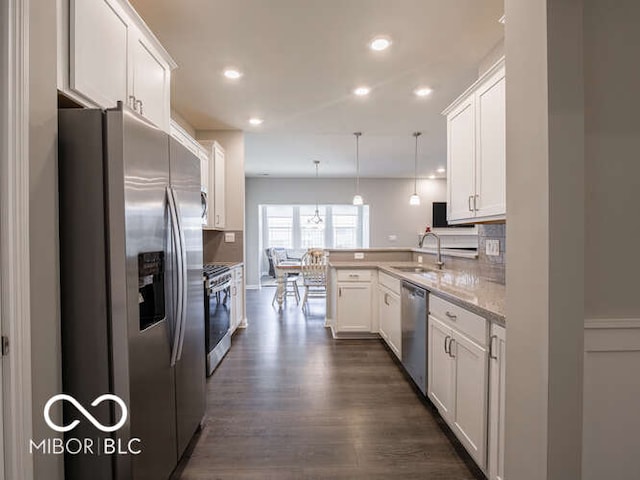 8866 Twain Ln, Indianapolis, IN 46239 - kitchen featuring stainless steel appliances, a peninsula, white cabinetry, dark wood-type flooring, and hanging light fixtures