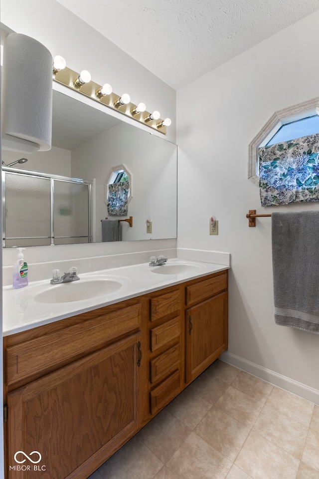 1016 W Creek Ridge Dr, Fountaintown, IN 46130 - bathroom with double vanity, a shower stall, tile patterned flooring, a textured ceiling, and healthy amount of natural light