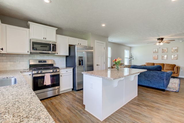 2500 Sand Hollow Dr, Lebanon, IN 46052 - kitchen with stainless steel appliances, wood finished floors, open floor plan, backsplash, and a kitchen island