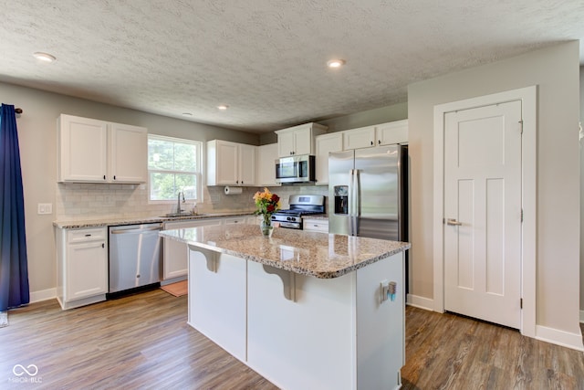 2500 Sand Hollow Dr, Lebanon, IN 46052 - kitchen featuring stainless steel appliances, white cabinets, light wood-type flooring, decorative backsplash, and a textured ceiling