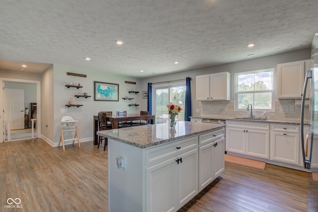 2500 Sand Hollow Dr, Lebanon, IN 46052 - kitchen featuring light wood finished floors, backsplash, a textured ceiling, a center island, and white cabinetry