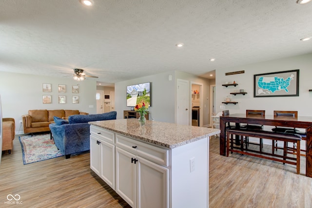 2500 Sand Hollow Dr, Lebanon, IN 46052 - kitchen featuring light wood-style flooring, a textured ceiling, white cabinets, a kitchen island, and ceiling fan