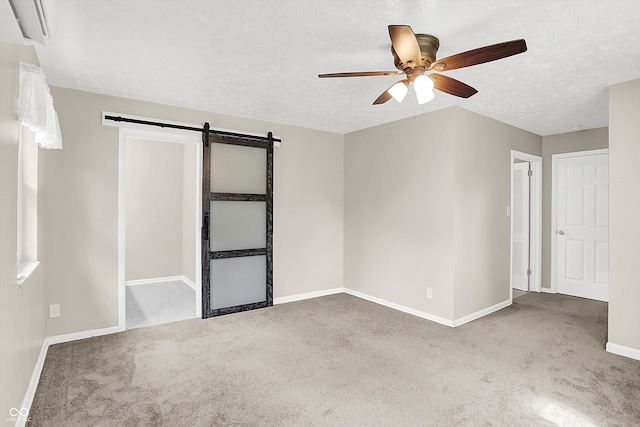 5015 Nowland Ave, Indianapolis, IN 46201 - unfurnished bedroom featuring a barn door, carpet, a textured ceiling, and a ceiling fan