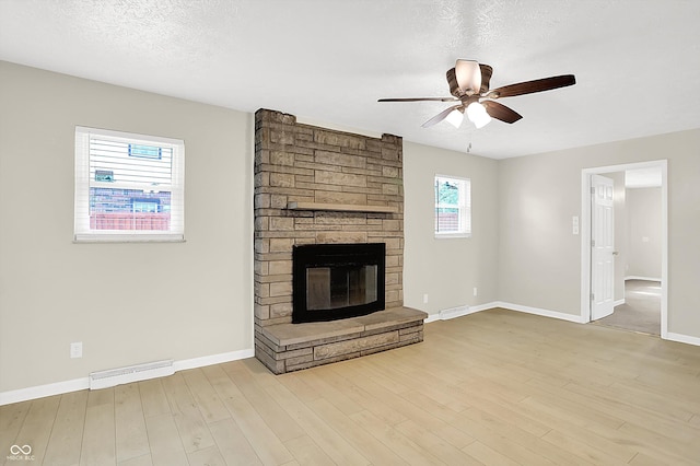 5015 Nowland Ave, Indianapolis, IN 46201 - unfurnished living room featuring ceiling fan, a stone fireplace, wood finished floors, and a textured ceiling