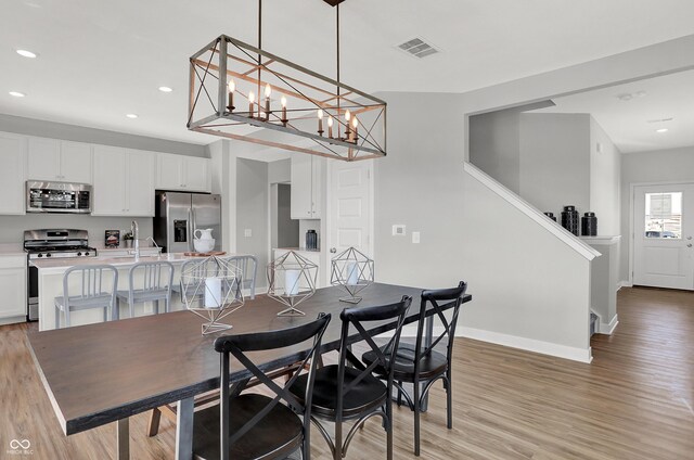 7687 Marin Pkwy, Cumberland, IN 46229 - dining area featuring light wood finished floors, recessed lighting, and a chandelier