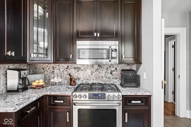 4455 Broadway St, Indianapolis, IN 46205 - kitchen featuring appliances with stainless steel finishes, dark brown cabinets, decorative backsplash, and glass insert cabinets
