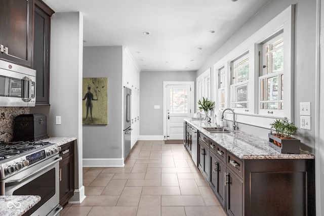 4455 Broadway St, Indianapolis, IN 46205 - kitchen featuring appliances with stainless steel finishes, dark brown cabinetry, light stone countertops, tasteful backsplash, and light tile patterned floors