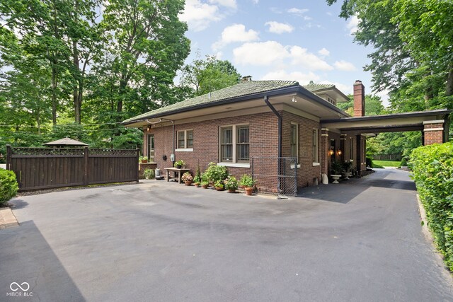 4455 Broadway St, Indianapolis, IN 46205 - view of side of property with a chimney, brick siding, and asphalt driveway