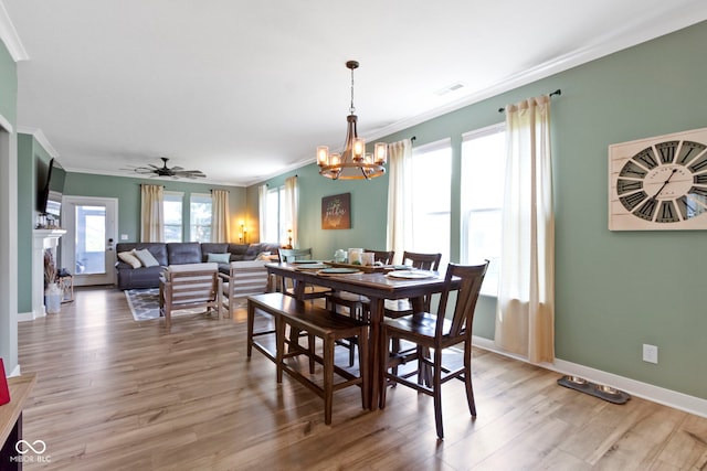 19959 Cowie Ln, Westfield, IN 46074 - dining area featuring crown molding, a chandelier, light wood-style floors, a fireplace, and ceiling fan