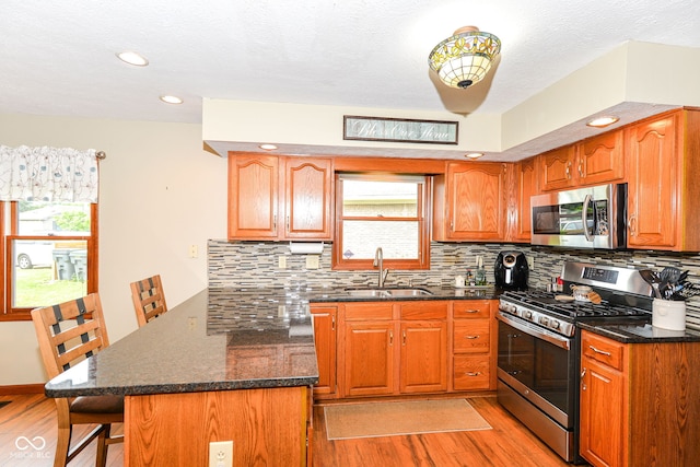 662 Leah Way, Greenwood, IN 46142 - kitchen with appliances with stainless steel finishes, a peninsula, light wood-type flooring, a breakfast bar, and recessed lighting