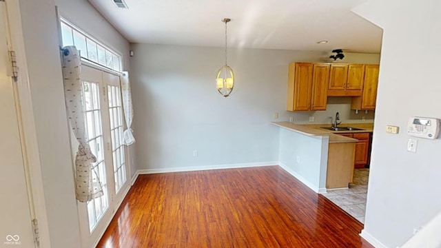 2259 Colfax Ln Unit 2259, Indianapolis, IN 46260 - kitchen with light wood-type flooring, light countertops, a peninsula, and pendant lighting