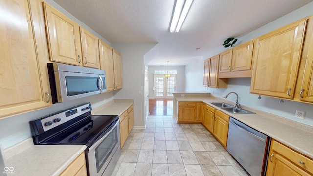 2259 Colfax Ln Unit 2259, Indianapolis, IN 46260 - kitchen featuring appliances with stainless steel finishes, light brown cabinetry, light countertops, a textured ceiling, and a peninsula