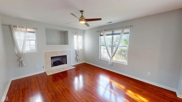 2259 Colfax Ln Unit 2259, Indianapolis, IN 46260 - unfurnished living room featuring healthy amount of natural light, wood finished floors, a tiled fireplace, and a ceiling fan
