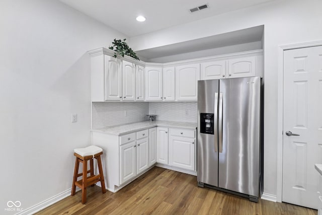 16636 Brownstone Ct, Westfield, IN 46074 - kitchen with stainless steel fridge with ice dispenser, wood finished floors, decorative backsplash, white cabinetry, and light stone countertops