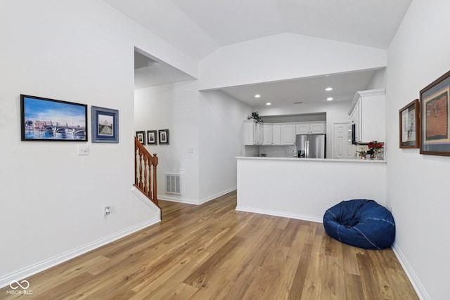 16636 Brownstone Ct, Westfield, IN 46074 - kitchen featuring stainless steel appliances, white cabinetry, light wood finished floors, lofted ceiling, and a peninsula