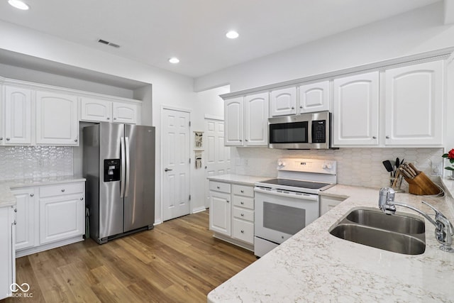16636 Brownstone Ct, Westfield, IN 46074 - kitchen with stainless steel appliances, tasteful backsplash, wood finished floors, light stone counters, and white cabinets