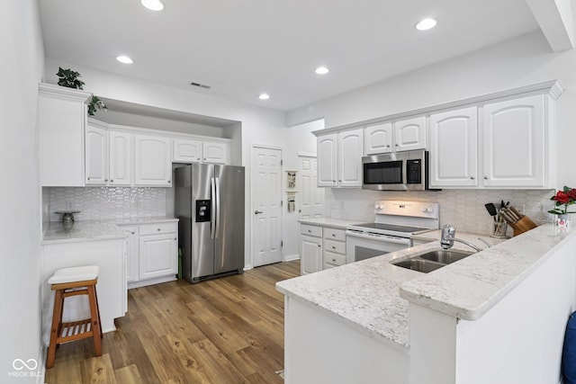 16636 Brownstone Ct, Westfield, IN 46074 - kitchen featuring stainless steel appliances, a peninsula, backsplash, white cabinetry, and recessed lighting
