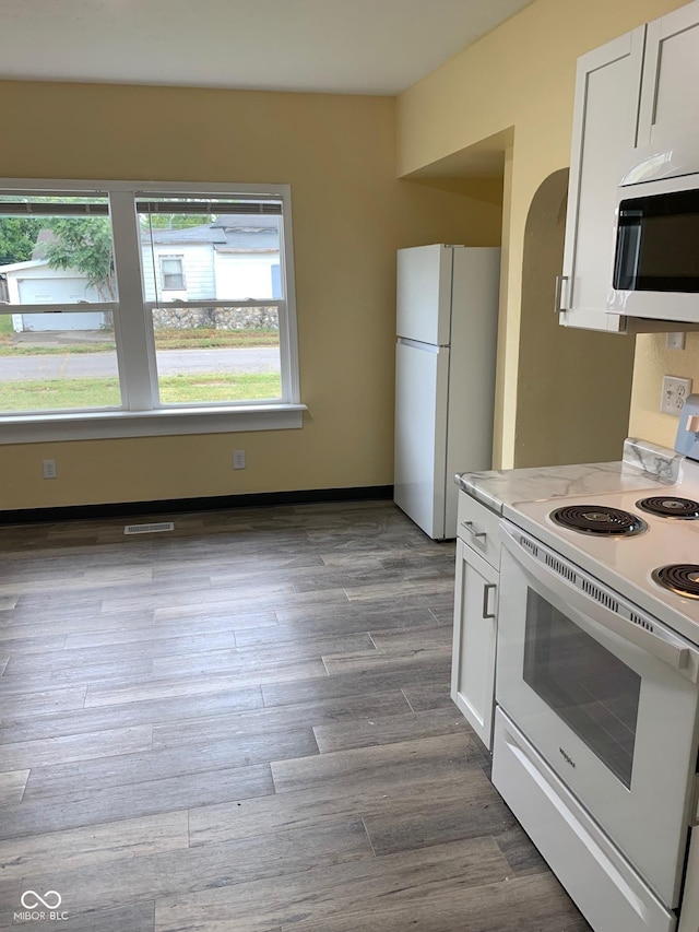 803 S Pershing Dr, Muncie, IN 47302 - kitchen featuring white appliances, healthy amount of natural light, white cabinets, and arched walkways