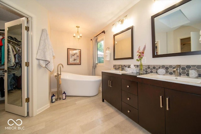 8550 Tidewater Ct, Indianapolis, IN 46236 - full bathroom with double vanity, a chandelier, a freestanding tub, a walk in closet, and tasteful backsplash