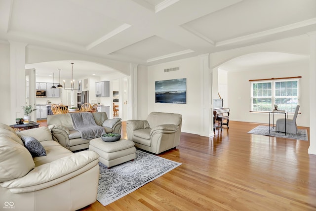 5761 Coopers Hawk Dr, Carmel, IN 46033 - living area with arched walkways, light wood-style floors, coffered ceiling, beamed ceiling, and a chandelier