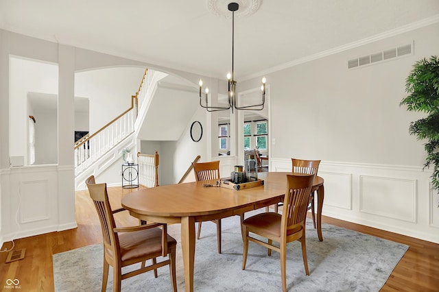 5761 Coopers Hawk Dr, Carmel, IN 46033 - dining space featuring wood finished floors, a chandelier, a wainscoted wall, stairs, and ornamental molding