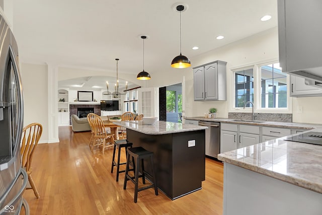 5761 Coopers Hawk Dr, Carmel, IN 46033 - kitchen featuring stainless steel appliances, light wood finished floors, a kitchen bar, open floor plan, and a kitchen island