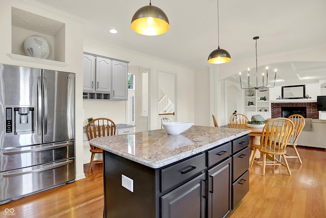 5761 Coopers Hawk Dr, Carmel, IN 46033 - kitchen with stainless steel fridge with ice dispenser, light wood-type flooring, open floor plan, decorative light fixtures, and crown molding