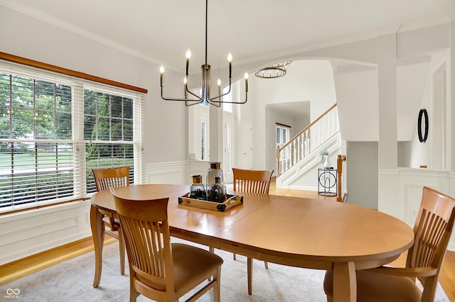 5761 Coopers Hawk Dr, Carmel, IN 46033 - dining room with crown molding, light wood-style floors, a chandelier, stairway, and wainscoting