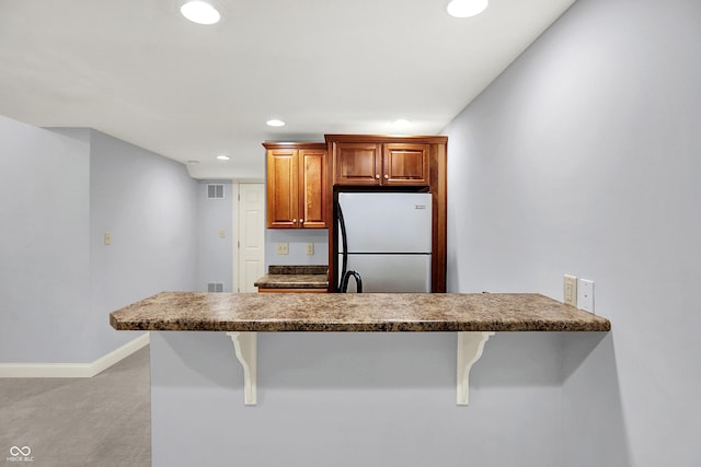2263 Glebe St, Carmel, IN 46032 - kitchen with freestanding refrigerator, a breakfast bar, recessed lighting, light carpet, and brown cabinets