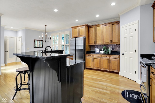 2263 Glebe St, Carmel, IN 46032 - kitchen featuring stainless steel appliances, brown cabinetry, light wood finished floors, a breakfast bar, and crown molding