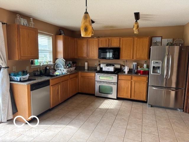 2230 Cedarmill Dr, Franklin, IN 46131 - kitchen featuring stainless steel appliances, light tile patterned floors, brown cabinetry, and pendant lighting