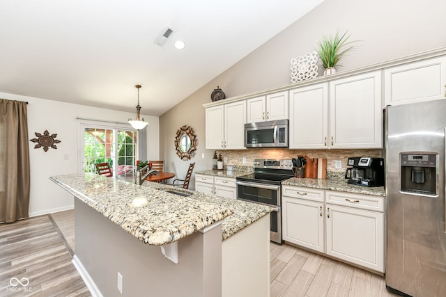 5765 White Pine Rd, Whitestown, IN 46075 - kitchen with appliances with stainless steel finishes, vaulted ceiling, tasteful backsplash, an island with sink, and light wood-style flooring