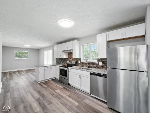 2853 S State Ave, Indianapolis, IN 46203 - kitchen with appliances with stainless steel finishes, a peninsula, white cabinetry, decorative backsplash, and a textured ceiling