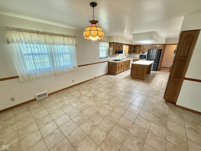 605 Redding Rd, Seymour, IN 47274 - kitchen featuring appliances with stainless steel finishes, light countertops, a kitchen island, light tile patterned floors, and decorative light fixtures