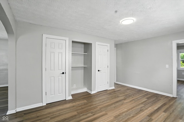 3609 N Keystone Ave, Indianapolis, IN 46218 - unfurnished bedroom featuring arched walkways, wood finished floors, a textured ceiling, and a closet
