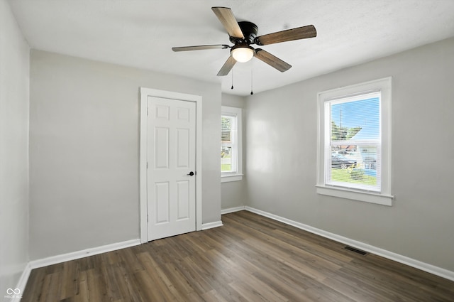 3609 N Keystone Ave, Indianapolis, IN 46218 - unfurnished bedroom with multiple windows, dark wood finished floors, and a ceiling fan