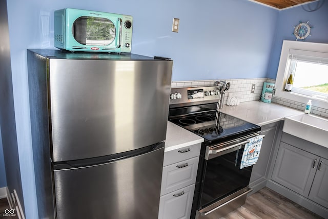 206 Olive St, Arcadia, IN 46030 - kitchen with stainless steel appliances, backsplash, wood finished floors, and gray cabinets