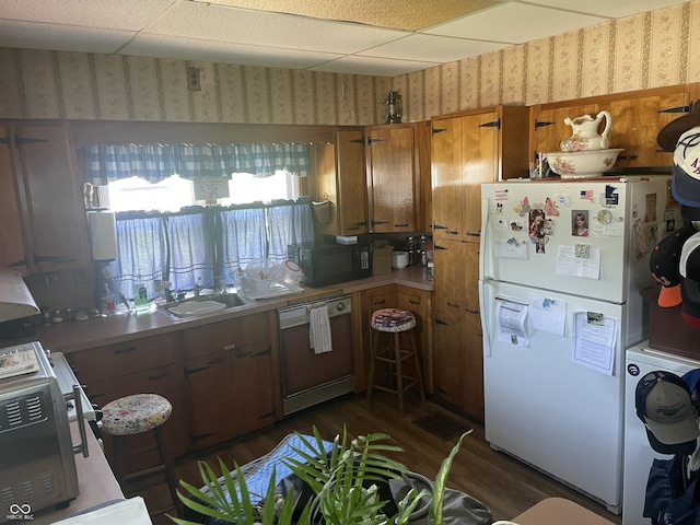 100 Durbin St, North Vernon, IN 47265 - kitchen with white appliances, wallpapered walls, washer / clothes dryer, dark wood-style flooring, and brown cabinetry