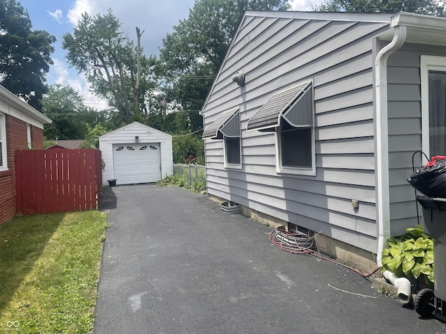 3642 N Dequincy St, Indianapolis, IN 46218 - view of home's exterior featuring an outdoor structure, asphalt driveway, and a garage