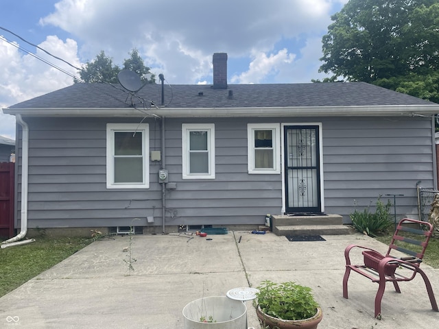 3642 N Dequincy St, Indianapolis, IN 46218 - rear view of house with a patio, a chimney, and roof with shingles