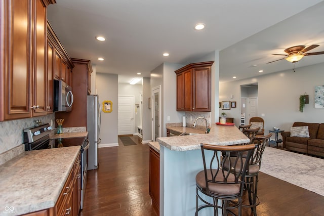 1976 Austin James Ln, Seymour, IN 47274 - kitchen featuring appliances with stainless steel finishes, a kitchen breakfast bar, open floor plan, dark wood finished floors, and backsplash