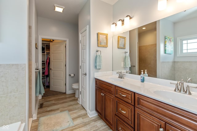 1976 Austin James Ln, Seymour, IN 47274 - bathroom with double vanity, wood finished floors, a walk in closet, and tile walls