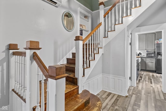 38 W Main St, Brownsburg, IN 46112 - staircase featuring wood finished floors, a wall mounted air conditioner, and wainscoting