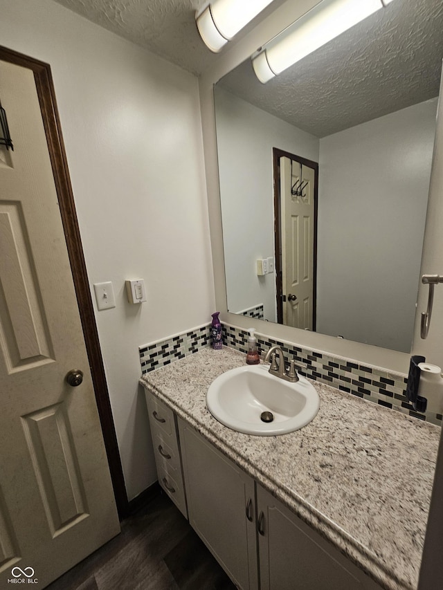 2239 Chevelle Ct, Anderson, IN 46012 - bathroom featuring wood finished floors, vanity, a textured ceiling, and decorative backsplash