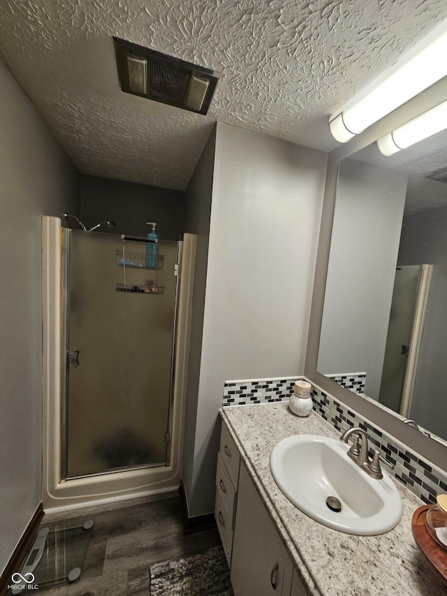 2239 Chevelle Ct, Anderson, IN 46012 - bathroom with a stall shower, vanity, wood finished floors, backsplash, and a textured ceiling