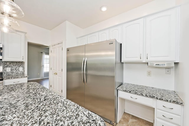 8909 Carnation Dr, Noblesville, IN 46060 - kitchen with stainless steel appliances, dark stone countertops, white cabinets, decorative backsplash, and built in desk