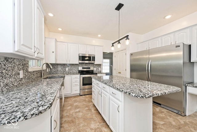 8909 Carnation Dr, Noblesville, IN 46060 - kitchen with appliances with stainless steel finishes, backsplash, white cabinetry, a kitchen island, and light stone counters