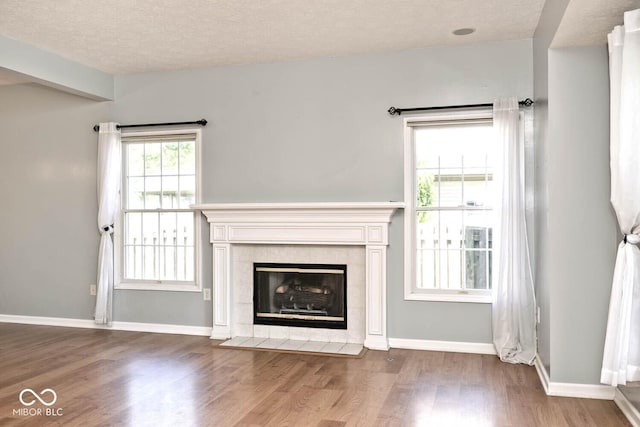 8909 Carnation Dr, Noblesville, IN 46060 - unfurnished living room with wood finished floors, a textured ceiling, and a tile fireplace