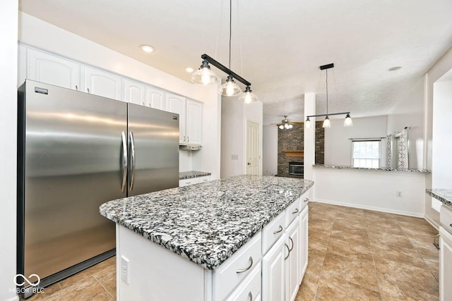 8909 Carnation Dr, Noblesville, IN 46060 - kitchen with freestanding refrigerator, a ceiling fan, light stone counters, white cabinets, and a kitchen island